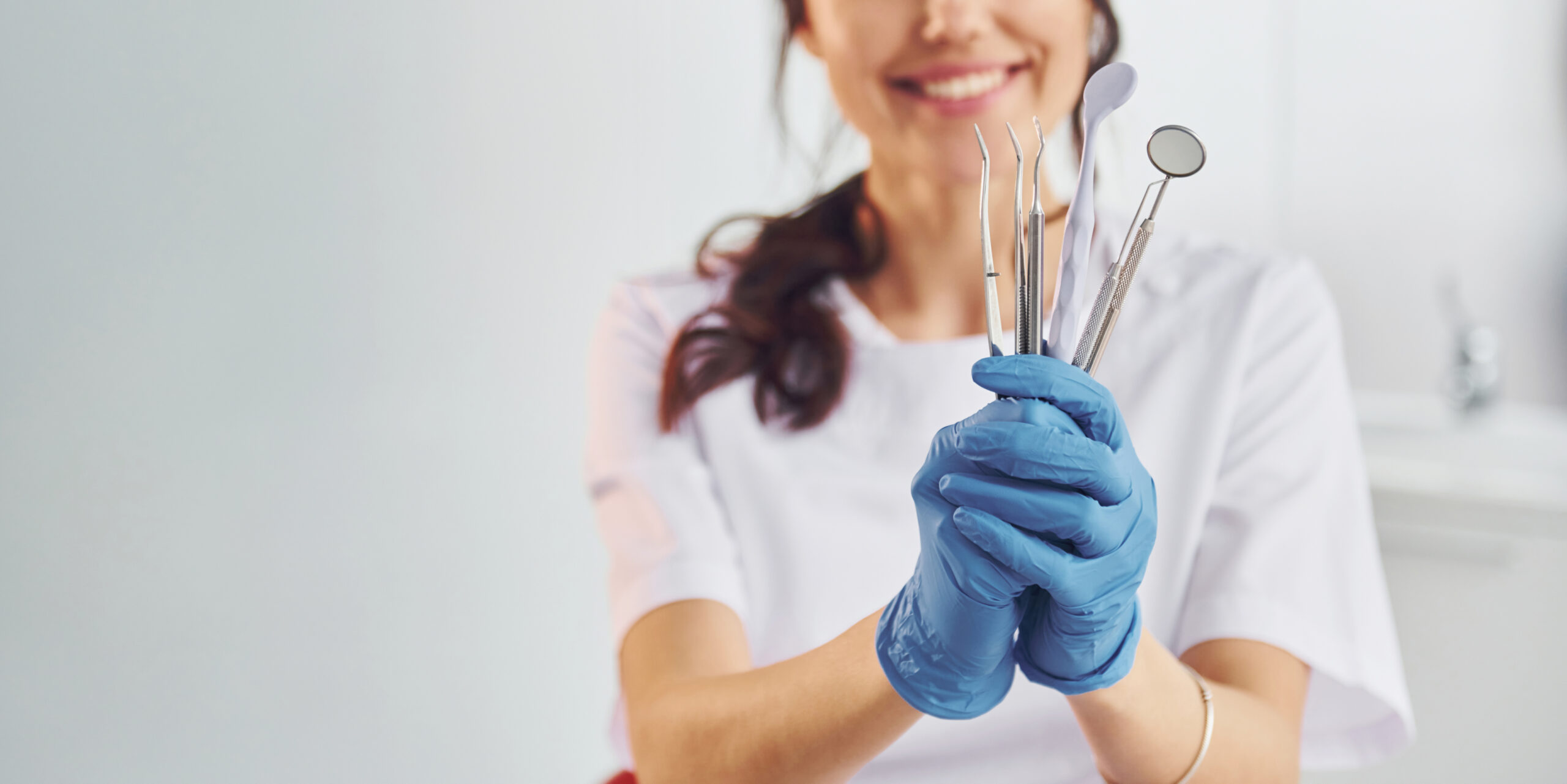 Portrait of professional female dentist with equipment that standing indoors.